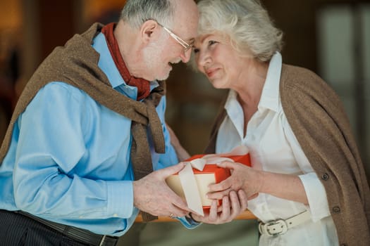 Senior couple hoding a gift together and smiling