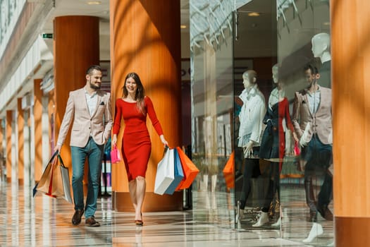 Happy beautiful young couple with shopping bags in mall