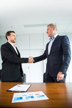 Business people handshake, businessmen hand shake, during meeting signing agreement contract standuing at desk, financial diagram, graph, business charts