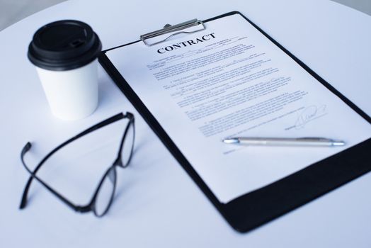 Business contract, coffee and glasses on table
