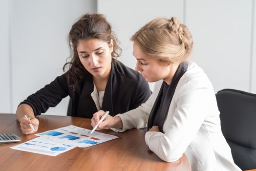 Business women working with financial diagrams, discussing financial reports at workplace