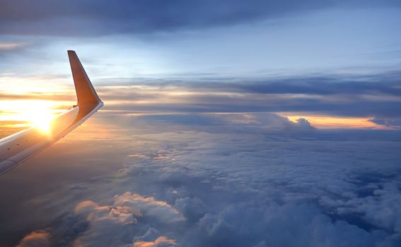 Wing of the plane on sky at sunset time