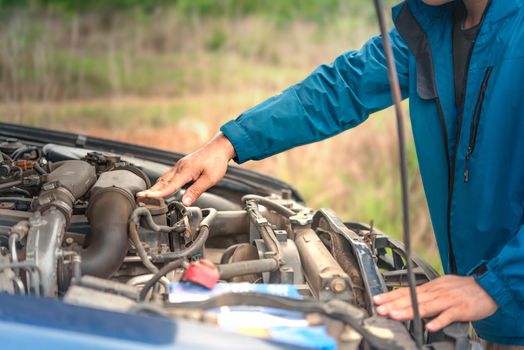 Asian stressed man having trouble with his broken car looking in frustration at failed engine