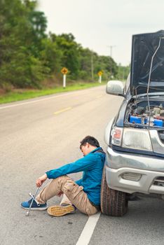 Asian stressed man having trouble with his broken car looking in frustration at failed engine