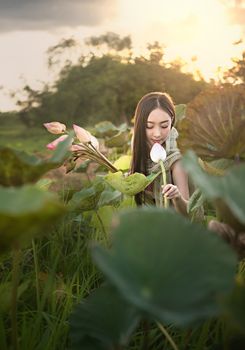 beautiful woman in traditional asian dresses harvesting water lilies in garden