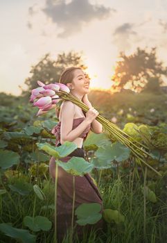 beautiful woman in traditional asian dresses harvesting water lilies in garden