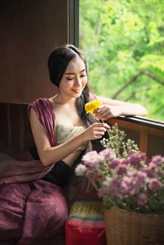 beautiful woman in traditional asian dresses holding flowers sitting near the windows