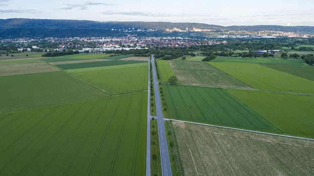 Aerial Capture of Countryside Landscape with Long Empty Road and City in Background