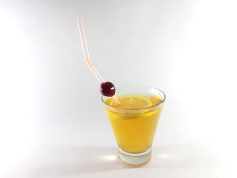 Drink with fruit in transparent container. Lemon and cherry for a snack. Yellow liquid in a glass. Photo for modern design. 