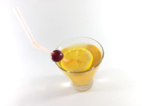 Drink with fruit in transparent container. Lemon and cherry for a snack. Yellow liquid in a glass. Photo for modern design. 