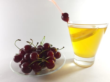 Drink with fruit in transparent container. Lemon and cherry for a snack. Yellow liquid in a glass. Photo for modern design. 