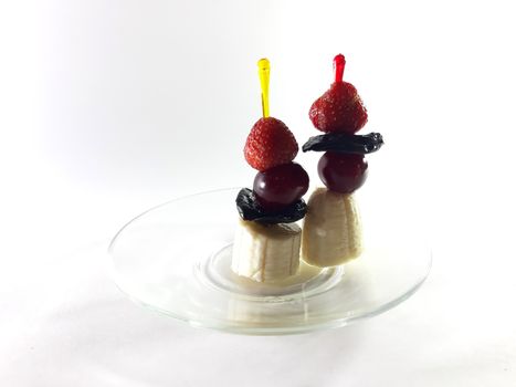 Dish for gourmet. Healthy food. Vegetarian foods on transparent plate. Berries and fruits. Lemon and cherry for a snack. Photo for modern design. Canapes made from bananas, strawberries and cherries.