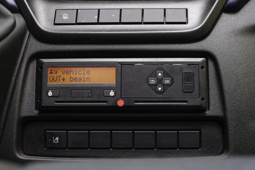 Digital tachograph display reads Vehicle Out Begin. No personal data. Tachograph in a van.