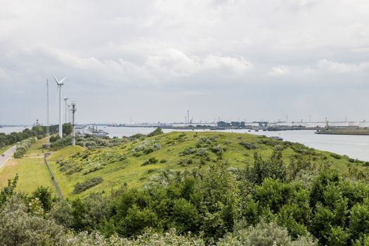 the harbor of rotterdam from the green dunes with the refinery and industry as background