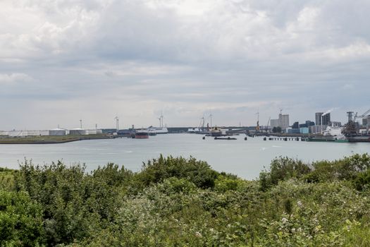 the harbor of rotterdam from the green dunes with the refinery and industry as background
