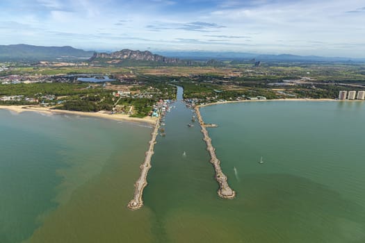 Aerial photo of Cha-am pier in  Phetchaburi Province, Thailand shows many fishing boats parked at the port, preparing to go to catch fish in the blue sea on a sunny day