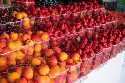 basket of red ripe strawberries and apricots for sale in the steet shop.