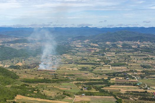 Aerial view of small area fire In the agricultural area With mountains on the horizon On a sunny day blue sky