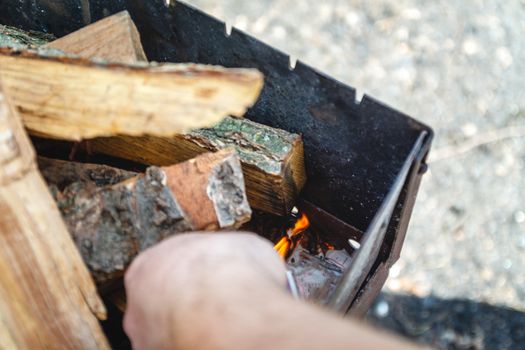 A man kindles a fire in a brazier with matches.