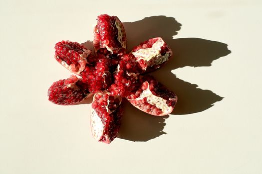 Garnet. Ripe red juicy pomegranate. Grains pomegranate fruit. Pomegranate cut in the form of a star. Lonely fruit on a light background. Hard daylight.