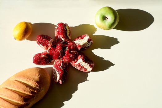Garnet. Bread. Lemon. An Apple. Bread long loaf and ripe red juicy pomegranate, green apple, yellow lemon lie separately on a white background. Grains pomegranate fruit.