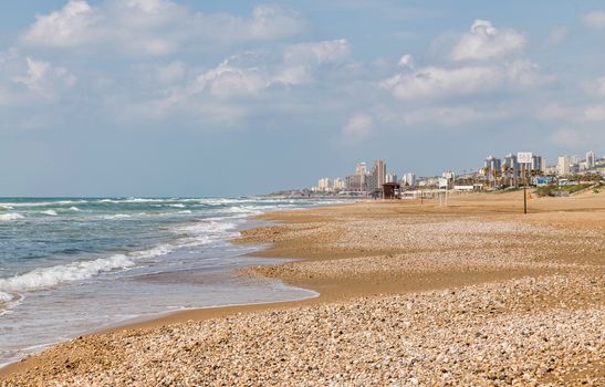 the haifa beach in israel with the city as background and a raw sea with waves at the coastline