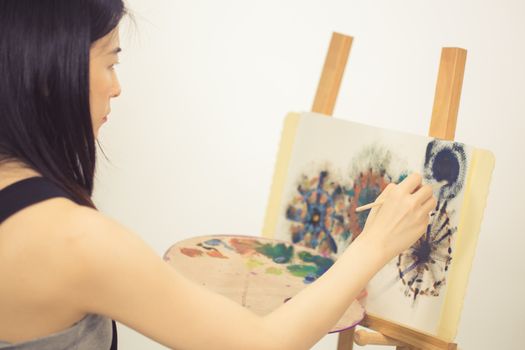 Female Asian artist painting on an easel