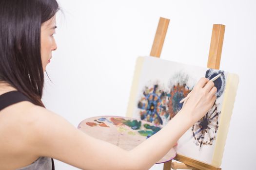 Female Asian artist painting on an easel