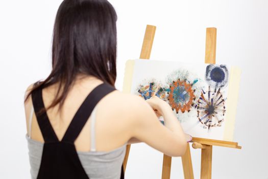 Female Asian artist painting on an easel