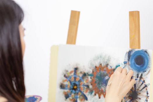 Female Asian artist painting on an easel