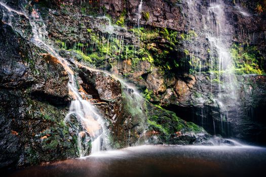 Cascading waterfalls into shallow rock pool deep in a ravine in the  Blue Mountains national park