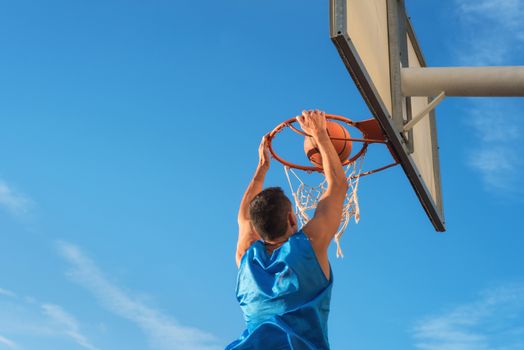 Street basketball athlete performing slam dunk on the court