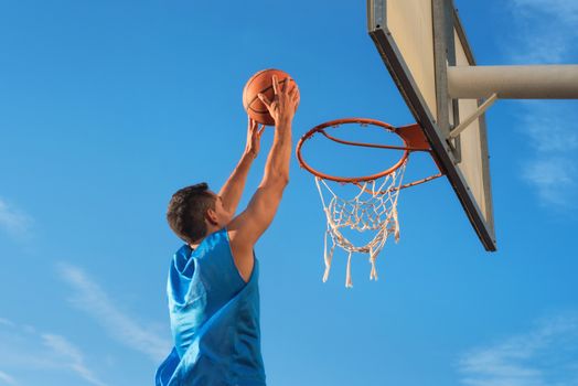 Street basketball athlete performing slam dunk on the court