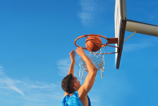 Street basketball athlete performing slam dunk on the court