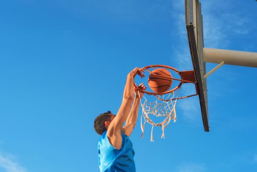 Street basketball athlete performing slam dunk on the court