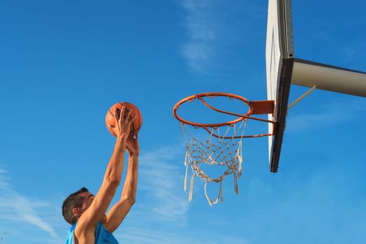 Street basketball athlete performing slam dunk on the court