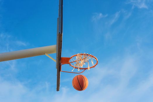 Basketball shield, ball flying to basket on blue sky background
