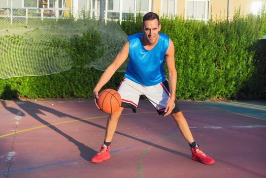 Young man athlete on basketball court dribbling