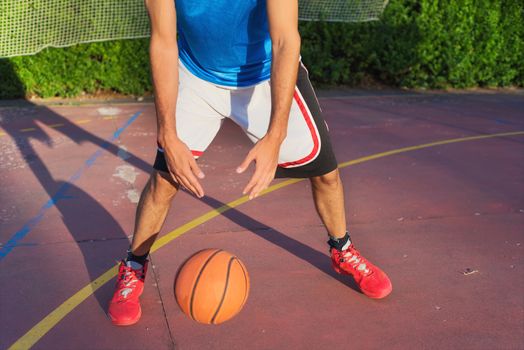 Young man athlete on basketball court dribbling