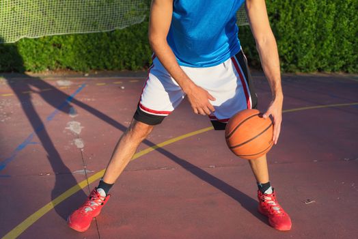 Young man athlete on basketball court dribbling