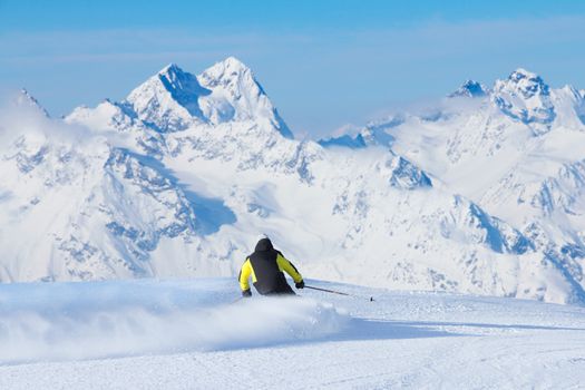 Skier skiing downhill in high mountains, rear view, Solden, Austria