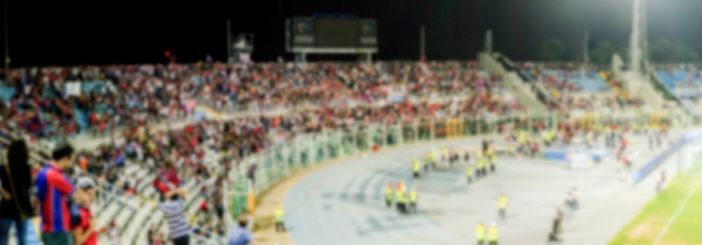 Defocused background with supporters in the stadium for football match at night. Intentionally blurred post production for bokeh effect