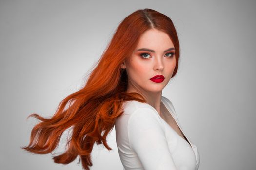 Gorgeous redhead girl with wavy hair beauty studio portrait