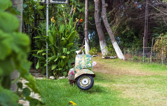 An old abandoned painted motorcycle in a garden at Corfu island, Greece.