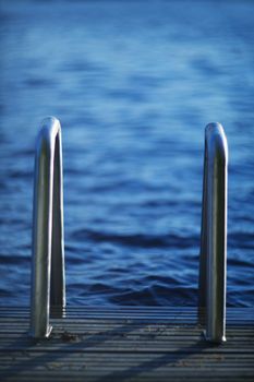 Wooden walkway jetty pier with railing for swimming in lake in Finland