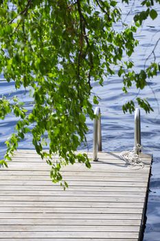 Wooden walkway jetty pier with railing for swimming in lake in Finland