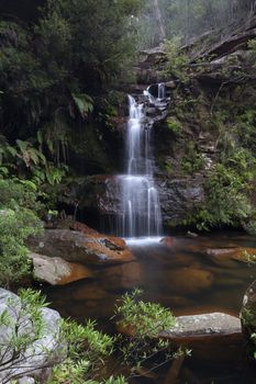 Beautiful ushland oasis with pretty waterfall tumbling into rock pool surrounded by Australian bushland