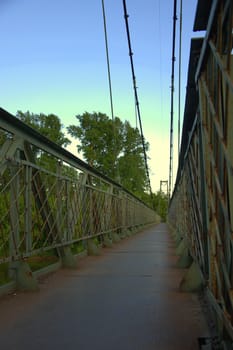 The pedestrian part of the suspension bridge against the evening sky.