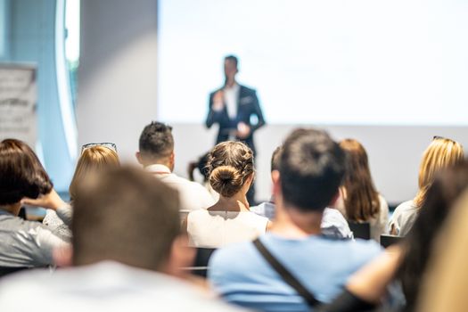 Male speaker giving a talk in conference hall at business event. Audience at the conference hall. Business and Entrepreneurship concept. Focus on unrecognizable people in audience.