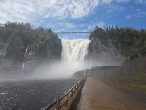 powerful waterfall flowing in Quebec, Canada with bridge and railing